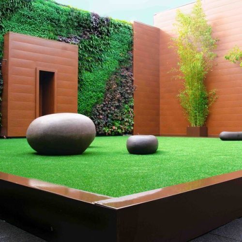 Un interno cortile a cui è stato applicato il servizio di verde, un tappeto verde con sopra dei sassi in stile zen