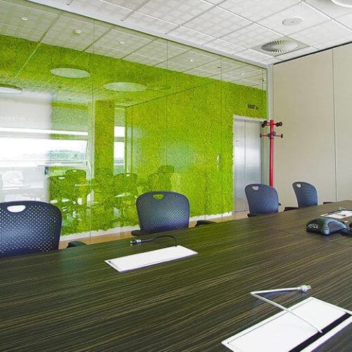 Tavolo riunioni con sullo sfondo una parete verde verticale separata da una vetrata