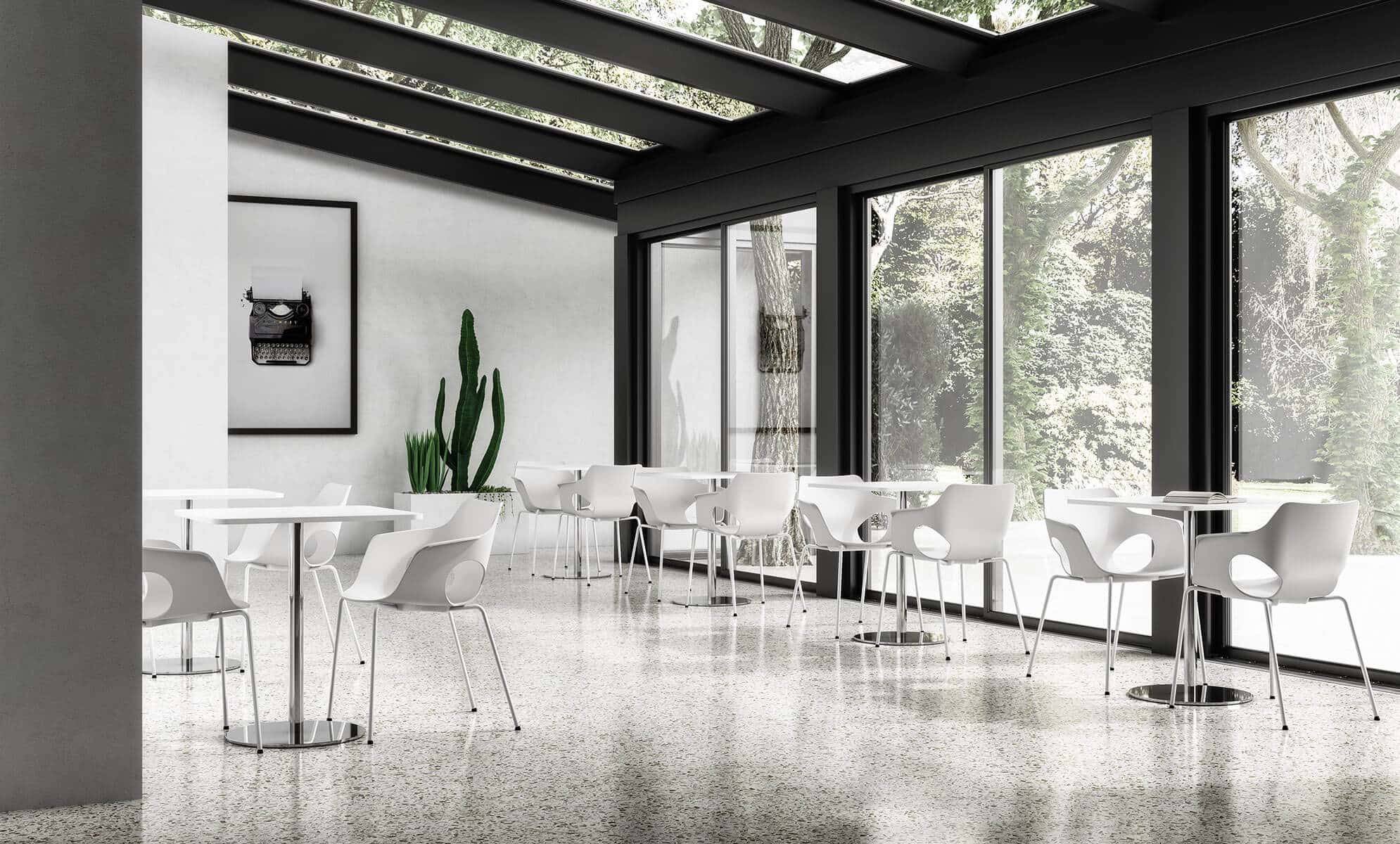 Una stanza luminosa con vetrate e tavolini con sedie bianche