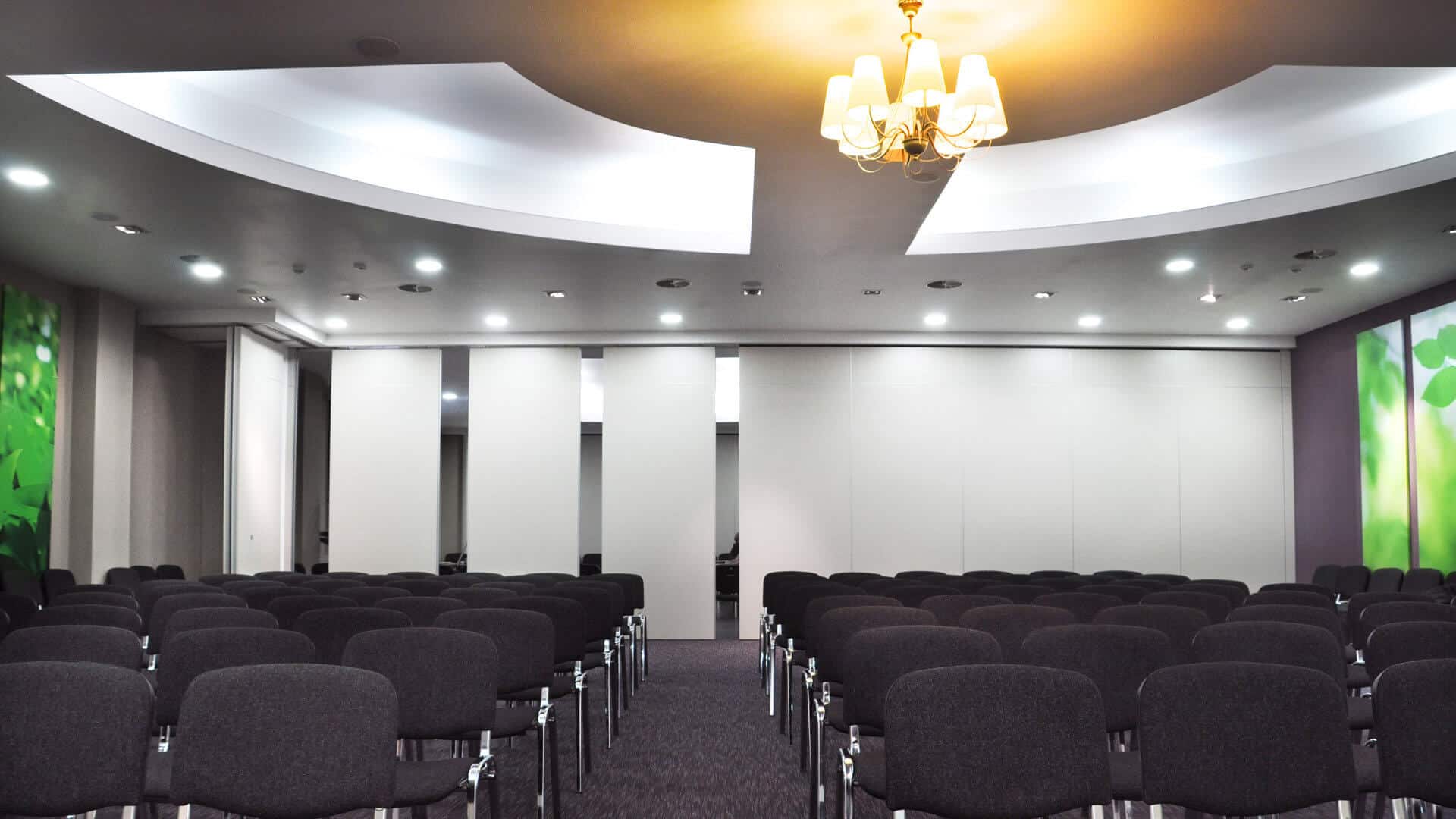 Sala conferenze arredata con sedie nere e pareti grigie