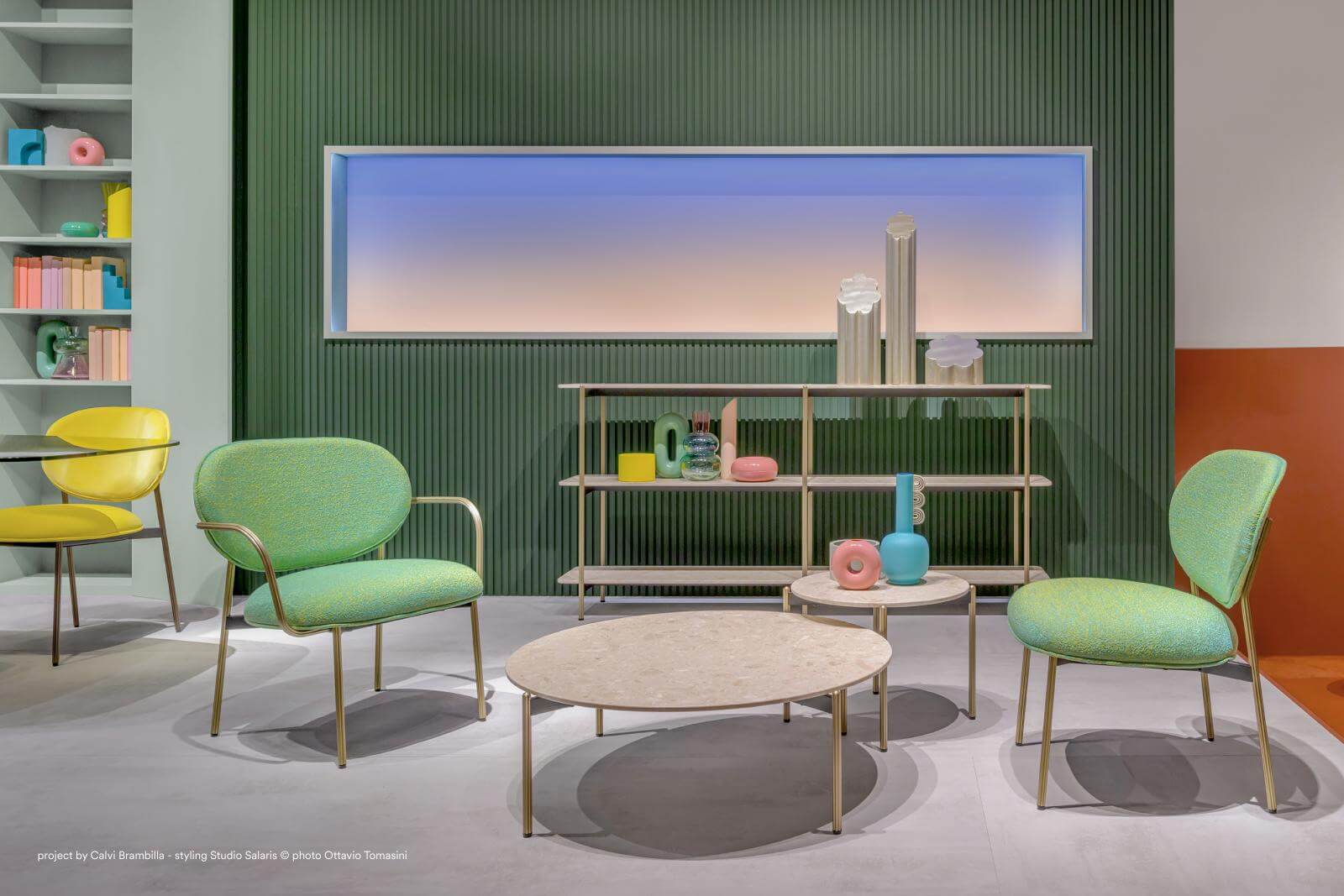 Ambientazione di design futurista, sedie verdi ai lati, tavolino grigio al centro, finestra in background